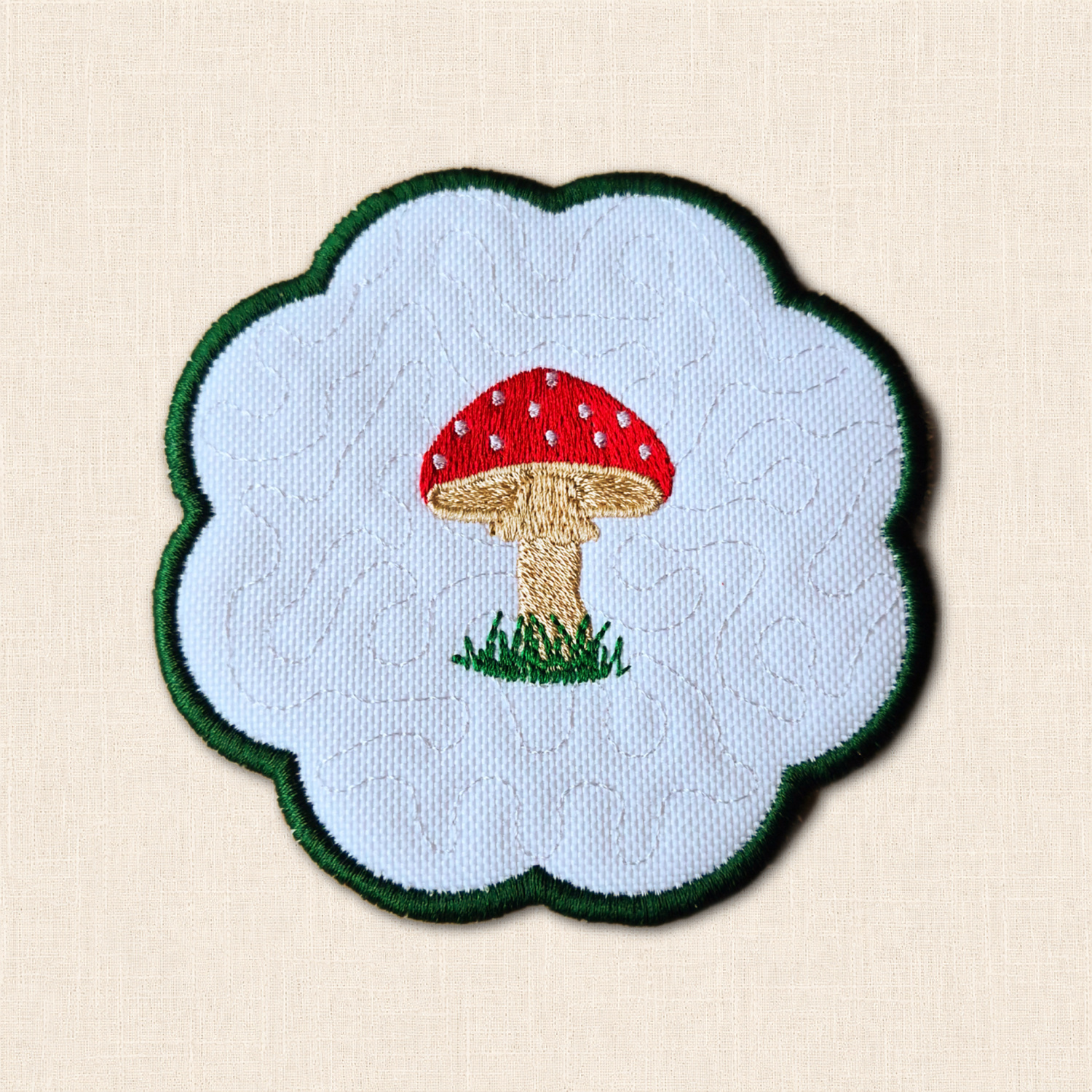 Embroidered Toadstool Candle Coaster with red spotted mushroom, grassy detail, stitched background and green scalloped edge