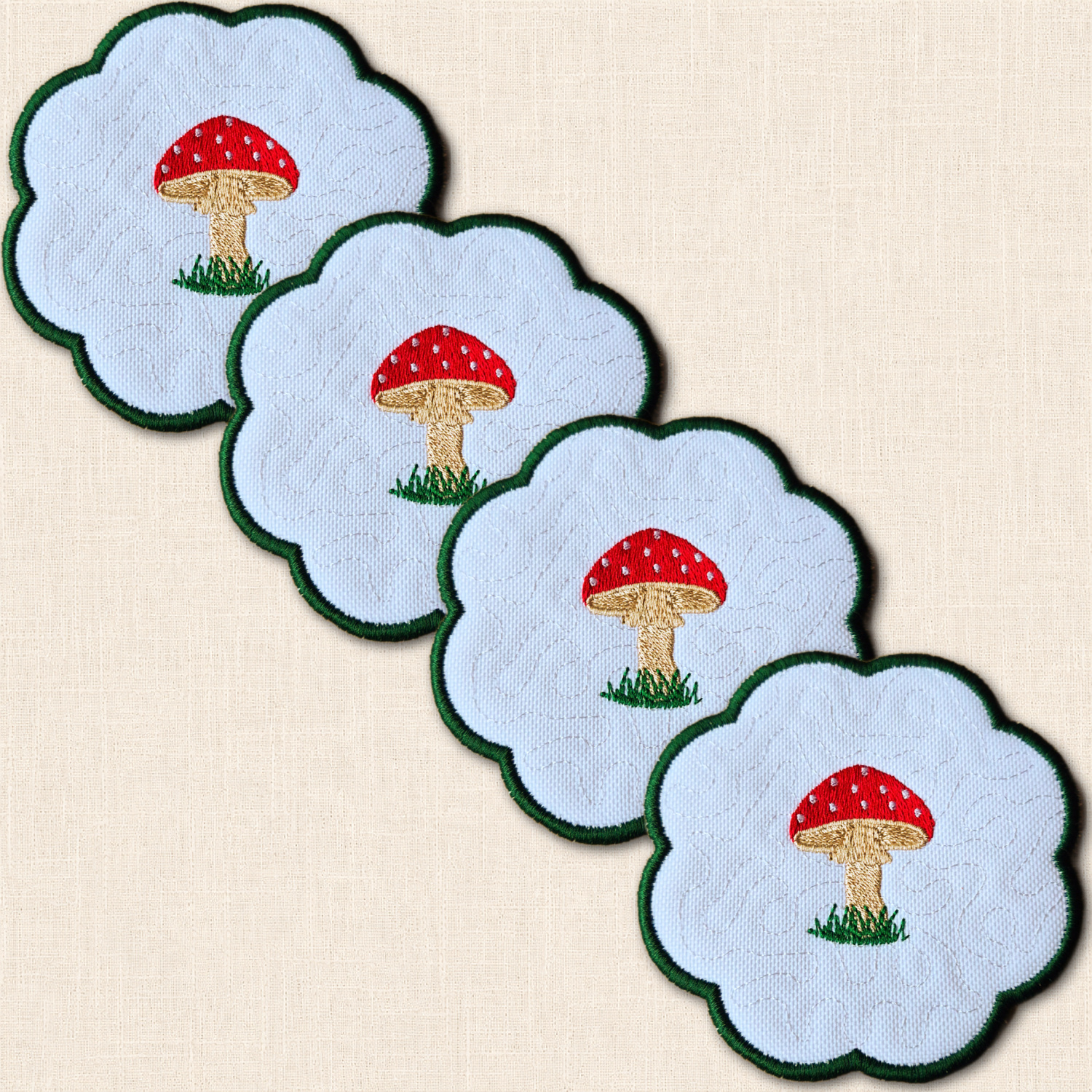 Set of four Toadstool Candle Coasters arranged together with embroidered red mushrooms and green borders