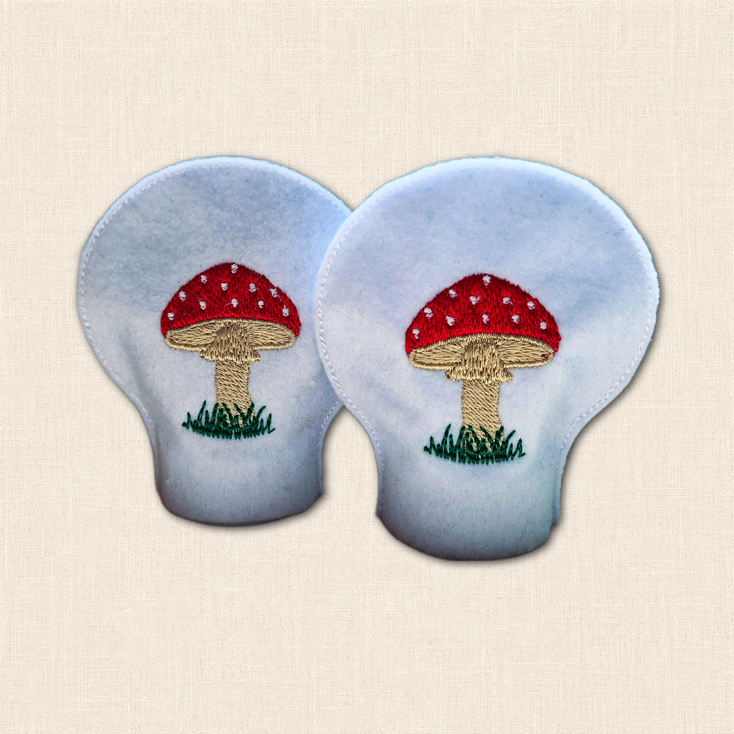 Pair of embroidered Toadstool Tealight Covers made from white felt with red spotted mushrooms and grassy details