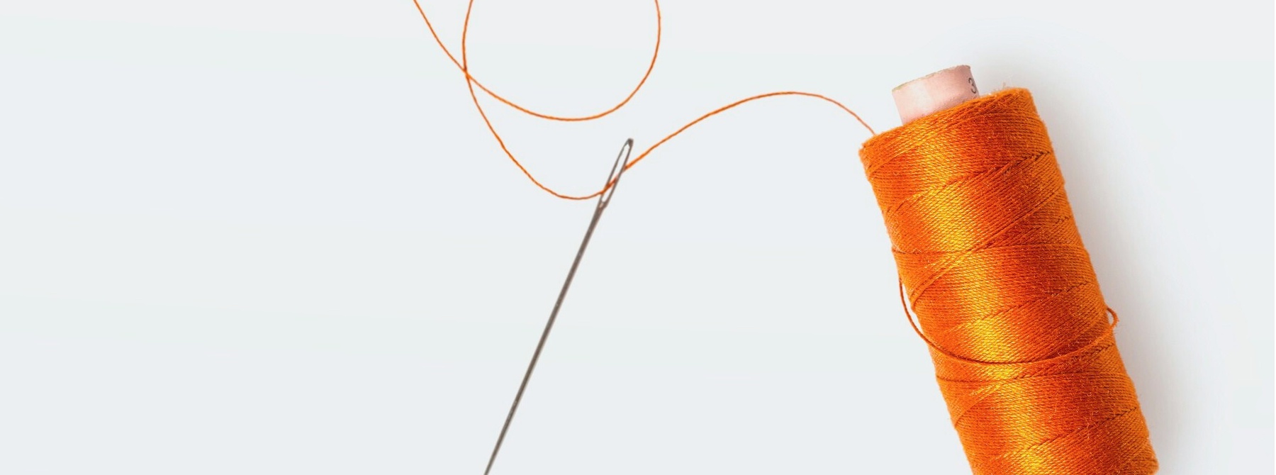 Orange thread spool and needle.