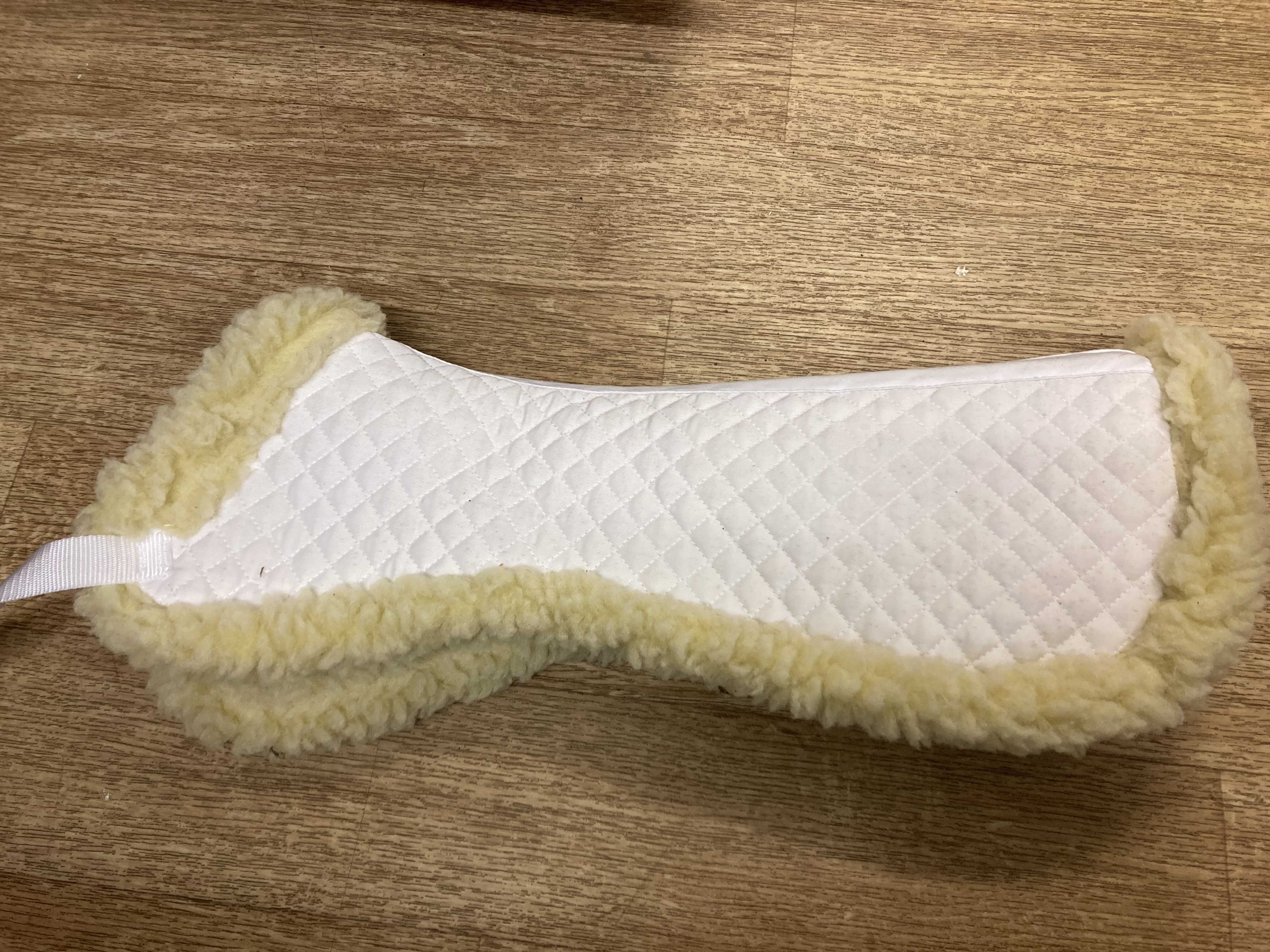 White faux sheepskin half pad. Shop soiled. 20.5” along spine
