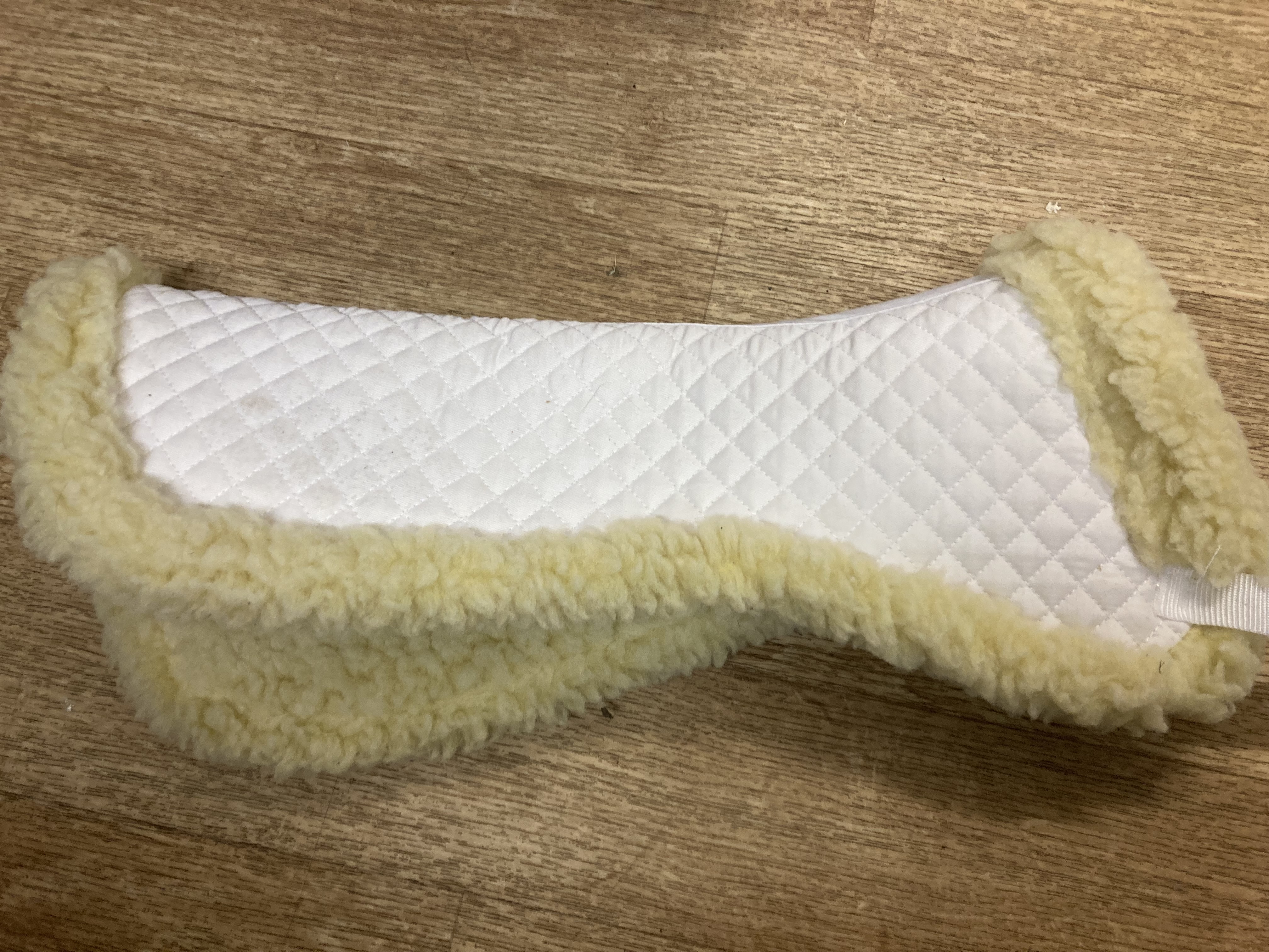 White faux sheepskin half pad. Shop soiled. 20.5” along spine