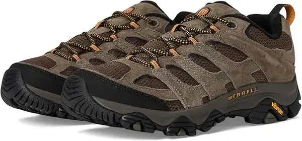 A close-up of the Merrell Moab 3 hiking shoe in Walnut on a rocky trail, showcasing the Vibram outsole.
