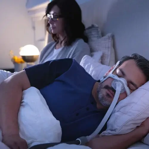 A person sleeping peacefully in bed while wearing the ResMed AirTouch N20 nasal CPAP mask.
