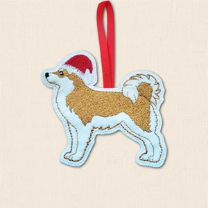 Akita Christmas dog decoration embroidered on felt with golden and white coat, red Santa hat and red hanging ribbon