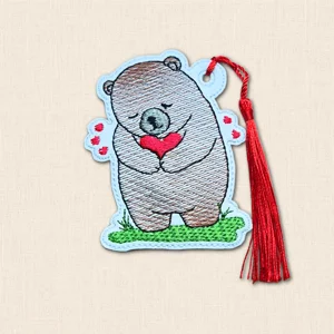 White faux leather bear bookmark embroidered in brown with a red heart and matching red silky tassel.