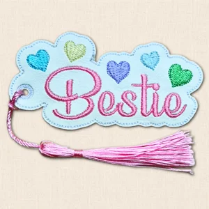 White faux leather Bestie bookmark embroidered in pink with colourful hearts and a matching pink silky tassel.