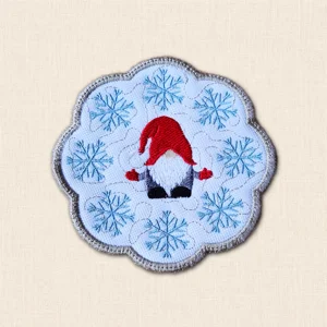 Christmas Gnome Candle Coaster with embroidered red-hat gnome, blue snowflakes, stitched background and grey scalloped edge