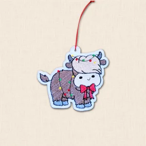 Highland Cow Christmas decoration embroidered on white felt with colourful Christmas lights, red bow and red hanging cord
