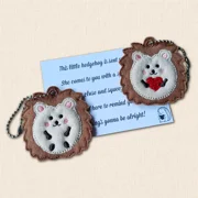 Two embroidered Hedgehog Pocket Pals displayed with a printed Hedgehugs comfort card, showing heart and open paws designs
