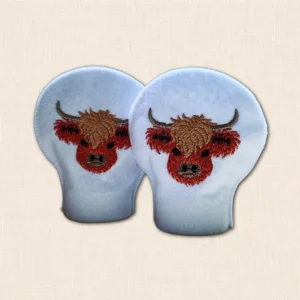 Pair of embroidered Highland Cow tealight covers made from white felt with stitched cow designs