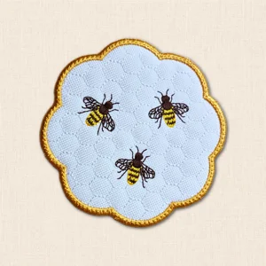 Honey Bee Candle Coaster with three embroidered bees, stitched honeycomb background and golden scalloped edging