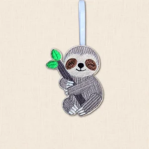 Brown and cream embroidered Knit Stitch Sloth Decoration holding a dark branch with bright green leaves, finished with a pale blue hanging ribbon.