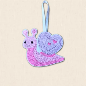 Pink and lilac embroidered Knit Stitch Snail Heart Decoration with a smiling face, heart-shaped shell and pale blue hanging ribbon.