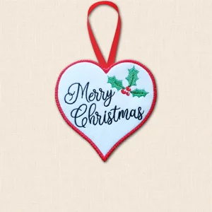Multilingual Merry Christmas heart decoration embroidered on white felt with black greeting, green holly, red berries and red stitched border