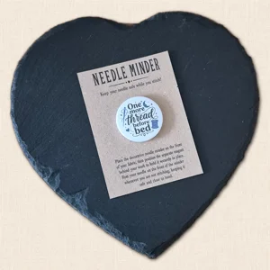 One More Thread Before Bed magnetic needle minder on a kraft presentation card displayed on a black heart-shaped slate