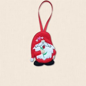 Felt gnome hanging decoration with a red hat and clothing, white beard, black boots and a red rose, finished with embroidered hearts and a red ribbon loop.