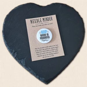 WIP Work In Progress magnetic needle minder on a kraft presentation card displayed on a black heart-shaped slate