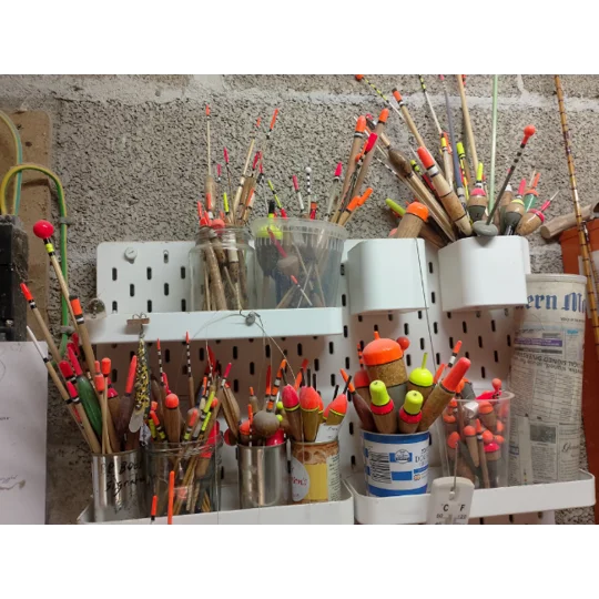 Assorted handmade fishing floats stored in jars in a traditional float maker’s workshop, showing mystery box stock selection