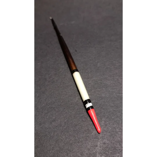 Close-up of a traditional handmade porcupine quill fishing float showing natural quill markings and painted tip.