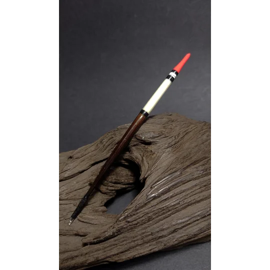 Handmade porcupine quill fishing float resting on driftwood with red tip by Ian Lewis.