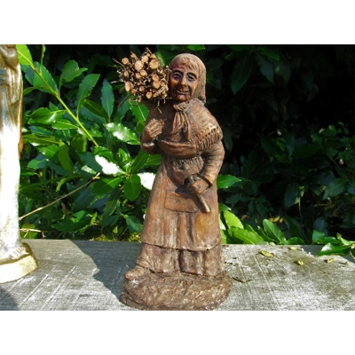 Folk art figurine of an old smiling country girl carrying a bundle of sticks armed with an axe ironware with great detail