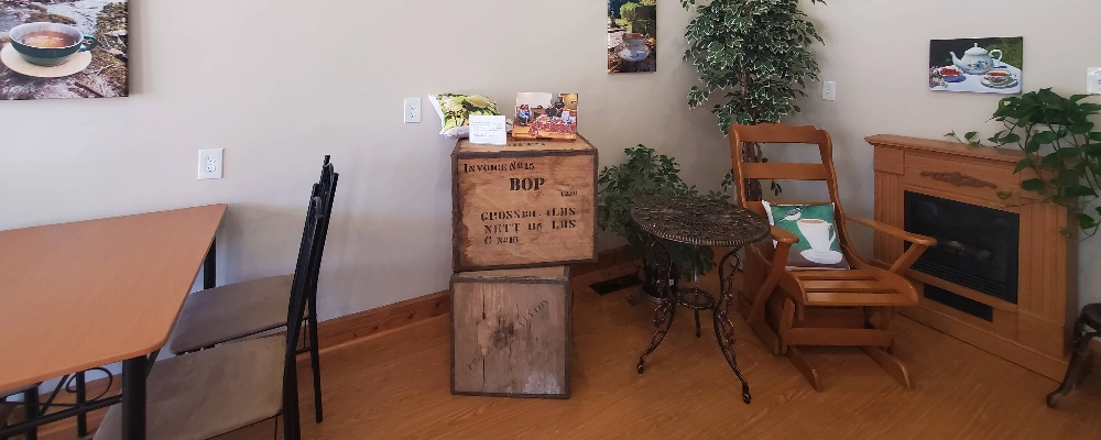 the cozy corner in the tea room with anique tea shipping crates, a rocking chair, and a fireplace looking heater,