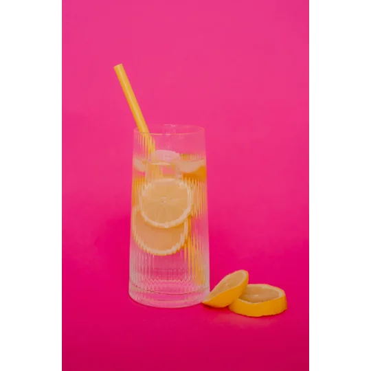 a yellow silicone straw in a glass with slices of lemon and ice