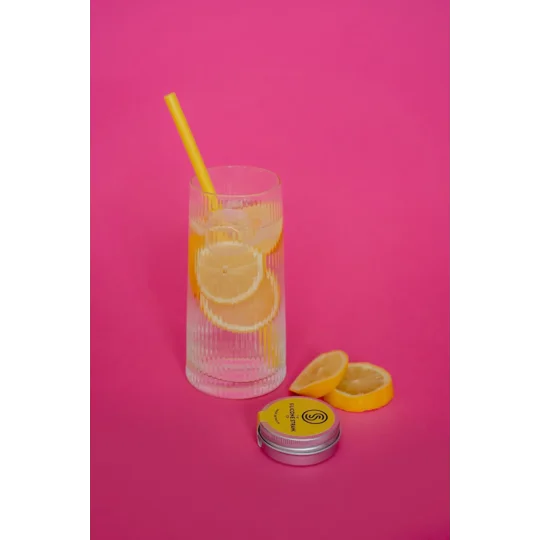 Bright image of a yellow silicone straw in a glass with ice and lemons