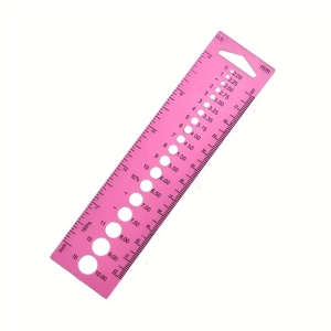 Pink knitting gauge with measurement markings on a white background.