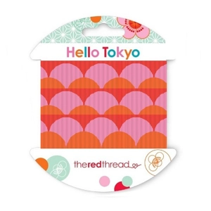 Red grosgrain ribbon with pink and orange fish scale design on a Hello Tokyo brand hangsell card.
