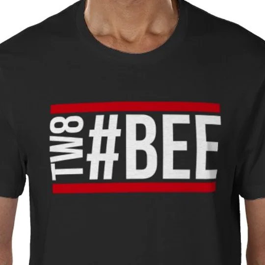 Black Bee Hashtag football fan shirt — Close-up product image of a black T-shirt with a large white “#BEE” and vertical “TW8” chest design, accented with vivid red stripes.