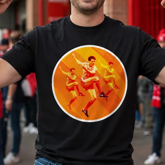 Black football T-shirt featuring a bold orange and yellow retro football player graphic, modelled by a fan outside a stadium