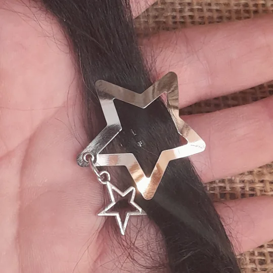 A miniature star snap clip for dolls with a dangling star charm attachment shown gripping dark doll hair for scale, suitable for custom adult collector dolls and fantasy styling