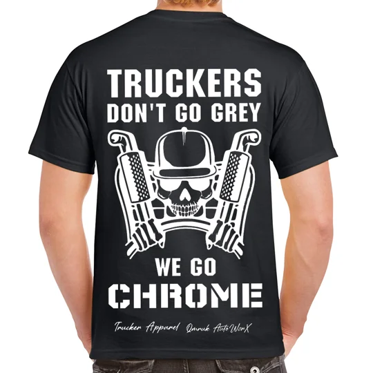 the back of a black t-shirt with white image of skeleton truck driver wearing a cap, holding a steering wheel with large truck exhausts behind him with white text that reads truckers don't go grey we go chrome and qmruk apparel and logos signed beneath