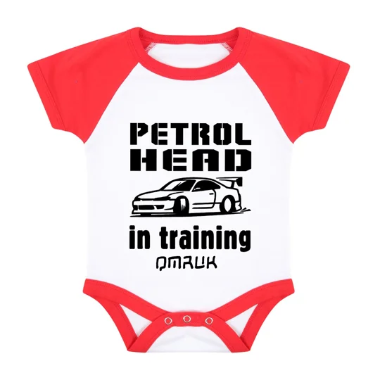 red baseball style babygrow onesie with black printed text reading little petrolhead in training and an image of a car all printed in black