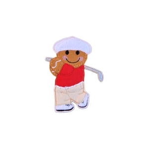 A gingerbread golfer character wearing a white cap, a red top, light trousers, and white shoes, holding a golf club over one shoulder and smiling cheerfully.