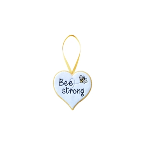 A white felt heart hanging decoration with a yellow stitched border and ribbon loop, featuring the words ‘Bee Strong’ and a small embroidered bee on the front.