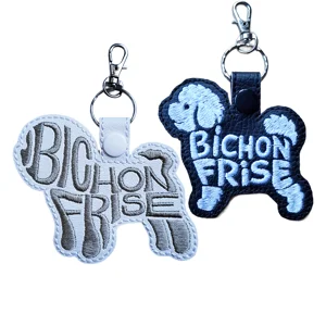 Black and white Bichon Frise dog word art keyrings made from faux leather with embroidered breed lettering and sturdy metal keyring fittings.
