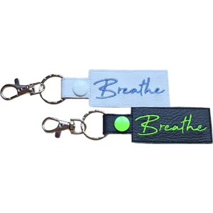 Black and white faux leather Breathe positive word keyrings with embroidered text and metal clip attachments.