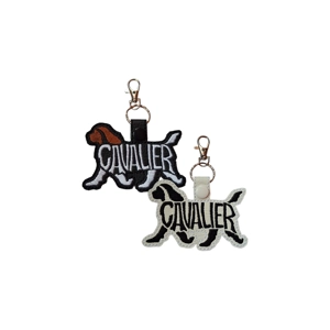 Embroidered Cavalier King Charles Spaniel keyrings shown in black and white faux leather, featuring stitched Cavalier lettering, dog silhouette shape, and metal clasp and keyring.