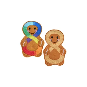 Two felt gingerbread characters on a plain white background. One features a stitched rainbow infinity symbol across the body, representing neurodiversity, while the other shows a stitched gold infinity symbol.