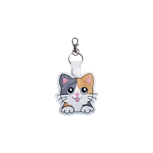 A kawaii-style calico cat keyring made from faux leather, featuring a smiling cat with large expressive eyes, stitched ears, whiskers, and paws, machine embroidered in grey, orange, white, and pink, finished with a metal keyring and lobster clasp.