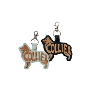 Two Collie dog-shaped keyrings made from faux leather, one in white with tan embroidery and one in black with tan embroidery. Both feature stitched word-art reading Collie, with a metal ring and lobster clasp attached at the top.
