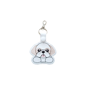 A kawaii-style Shih Tzu dog keyring with a cuddly expression, featuring an embroidered puppy face with floppy ears, paws resting at the front, and a metal keyring with lobster clasp attached.