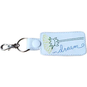 White faux leather Dandelion Dream positive word keyring with embroidered dandelion seed design, blue dream wording and silver metal clip.