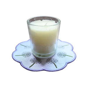 Embroidered dandelion seed head candle mat with a scalloped purple edge, shown with a cream candle in a glass holder on top.