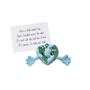 Earth Heart Pocket Hug Keyring with a smiling heart-shaped globe, blue oceans and green continents, outstretched blue felt arms, and a silver keyring clasp. Includes a keepsake card with a handwritten-style message: “Here’s a little pocket hug that’s travelled across the miles…”