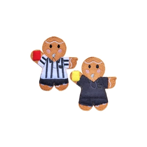 Two felt gingerbread referee characters with stitched facial details and an embroidered whistle. One wears a black-and-white striped shirt and holds a red card, while the other wears a plain black shirt and holds a yellow card.