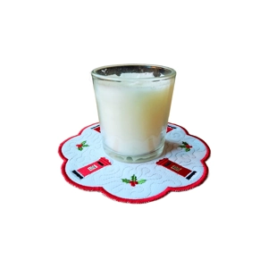A white scalloped candle mat embroidered with red post boxes and holly, shown with a glass candle on top.